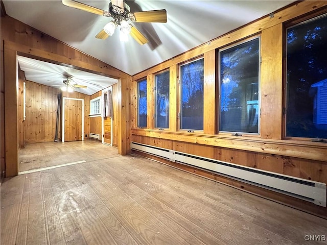 interior space featuring wood walls, a ceiling fan, vaulted ceiling, wood-type flooring, and a baseboard heating unit