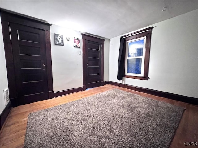 unfurnished room with visible vents, baseboards, and wood finished floors