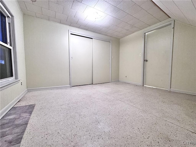 unfurnished bedroom with a closet, baseboards, and speckled floor