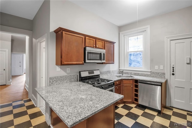 153 Allen St, Buffalo, NY 14201 - kitchen featuring appliances with stainless steel finishes, a peninsula, brown cabinetry, light floors, and a sink