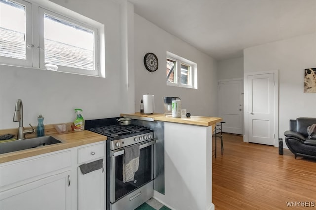 153 Allen St, Buffalo, NY 14201 - kitchen featuring light wood-type flooring, butcher block counters, white cabinets, stainless steel gas stove, and a sink
