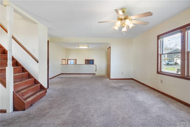 unfurnished living room featuring carpet flooring, baseboards, a ceiling fan, and stairway