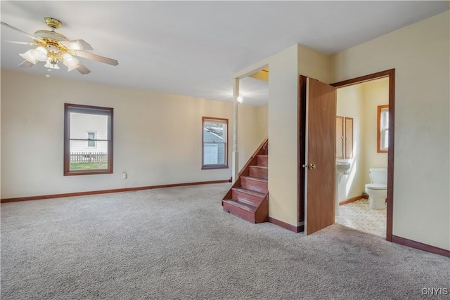 spare room with baseboards, ceiling fan, carpet, and stairs