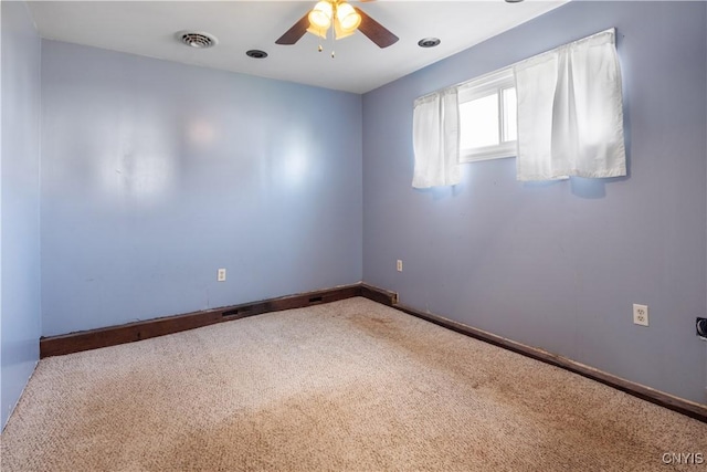 carpeted empty room featuring baseboards, a ceiling fan, and visible vents