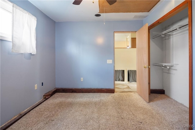 unfurnished bedroom with carpet flooring, a closet, attic access, and a ceiling fan
