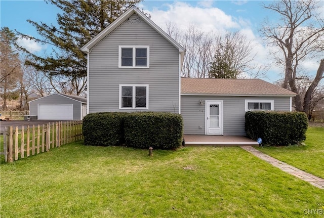 rear view of house with a garage, an outdoor structure, fence, and a lawn