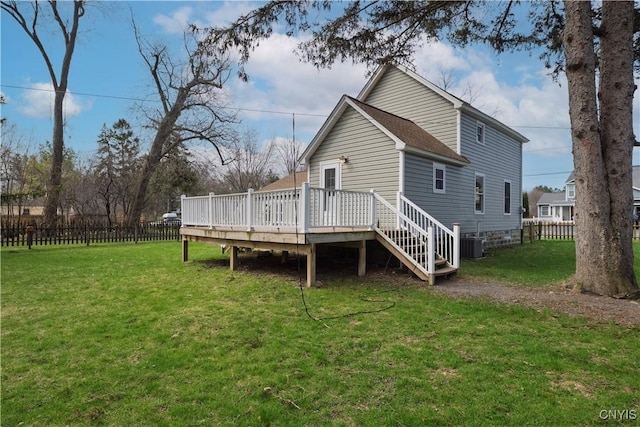 rear view of house with roof with shingles, a wooden deck, fence, and a lawn