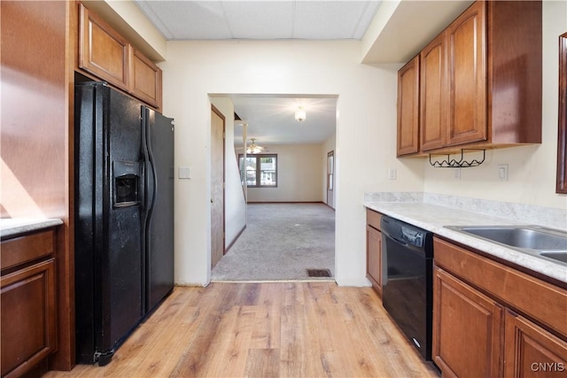 kitchen with brown cabinets, visible vents, light countertops, and black appliances