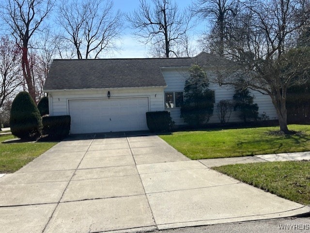 view of front of home with an attached garage, concrete driveway, and a front lawn