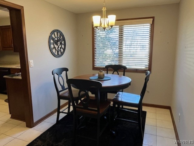 dining area with an inviting chandelier, light tile patterned flooring, and baseboards