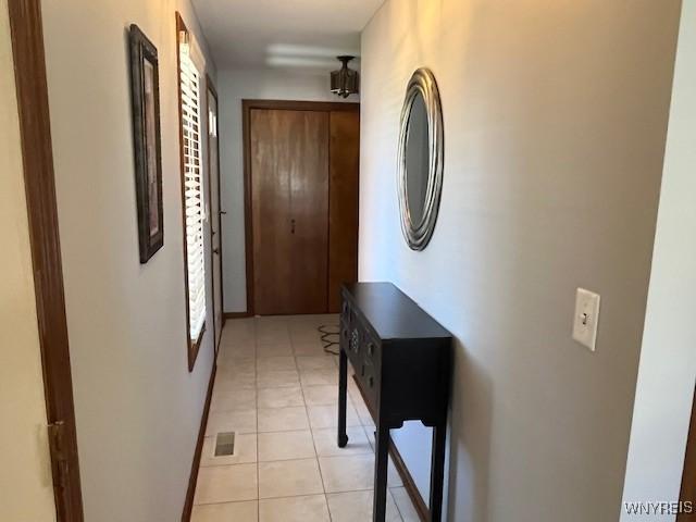 hall with light tile patterned flooring, baseboards, and visible vents