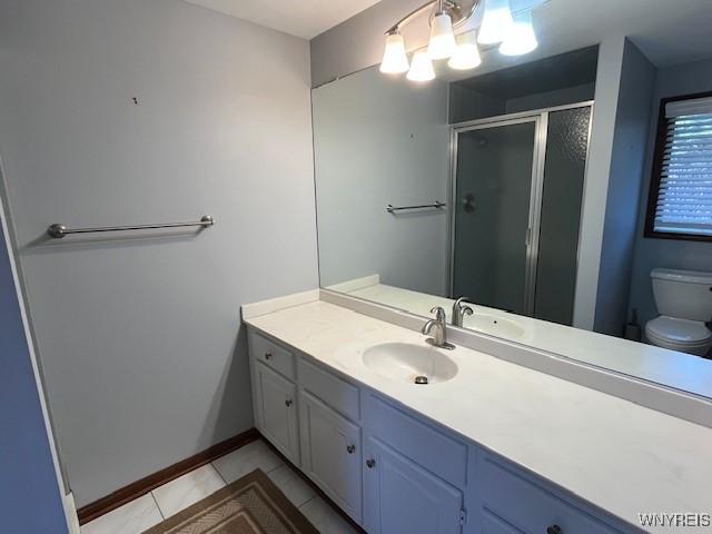 bathroom featuring toilet, vanity, tile patterned floors, a shower stall, and baseboards