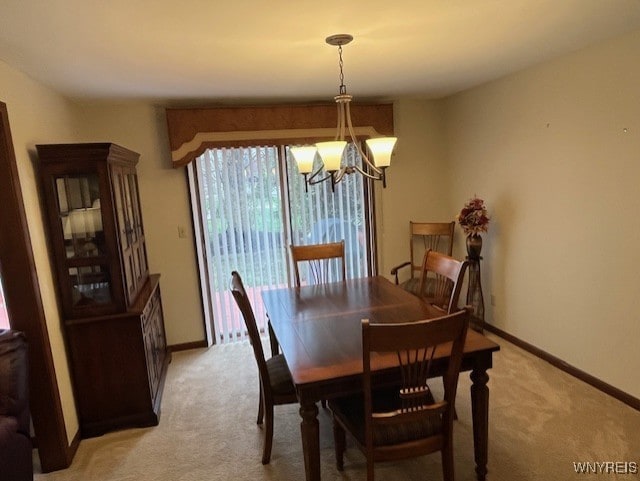 dining space with baseboards, a chandelier, and light colored carpet