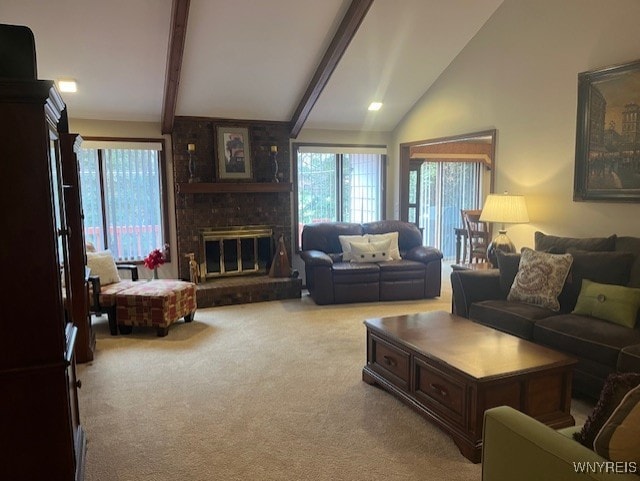 living area with a brick fireplace, carpet, a healthy amount of sunlight, and vaulted ceiling with beams