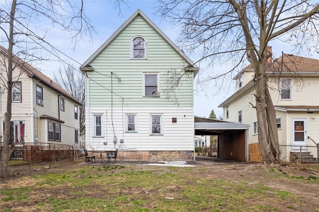 rear view of house featuring a carport and fence