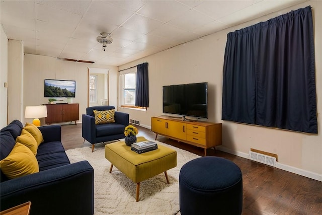 living area with visible vents, baseboards, and wood finished floors