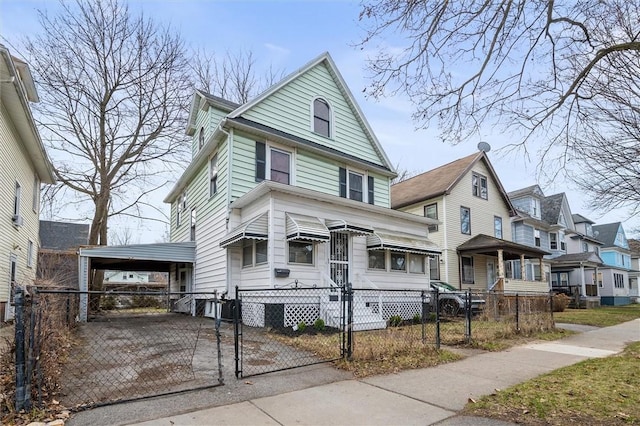 traditional style home with a fenced front yard, an attached carport, a gate, and aphalt driveway