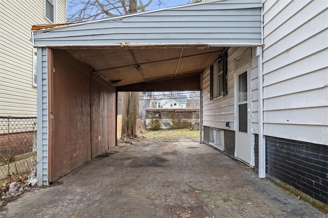 view of parking with a carport, fence, and aphalt driveway