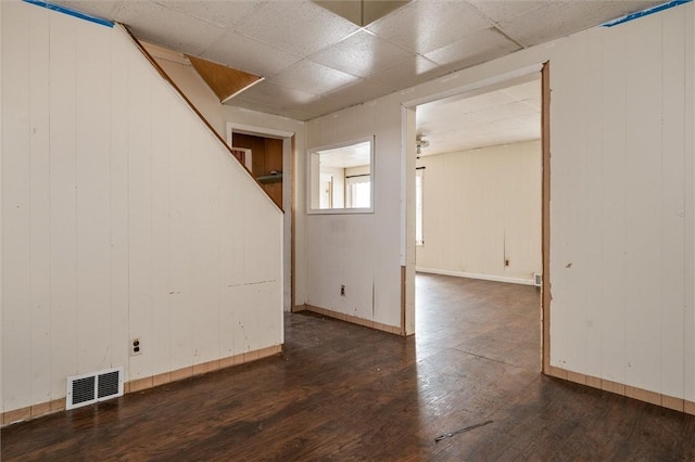 spare room with wood-type flooring, visible vents, a drop ceiling, and baseboards