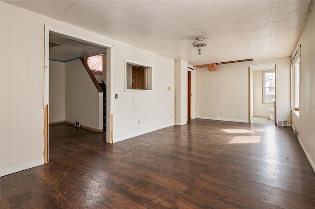 empty room featuring baseboards, dark wood finished floors, and visible vents