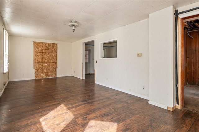 spare room with baseboards and wood finished floors
