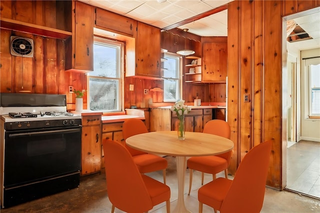 kitchen with wooden walls, visible vents, brown cabinetry, and range with gas stovetop