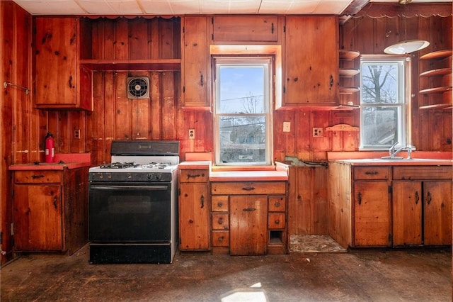 kitchen with range with gas cooktop, light countertops, open shelves, and wooden walls