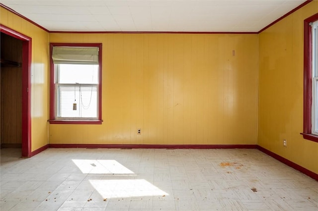 spare room featuring ornamental molding, baseboards, and light floors