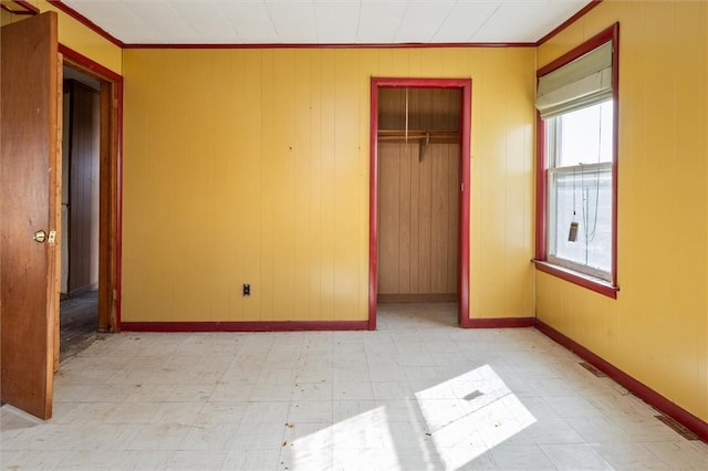 unfurnished bedroom with ornamental molding, a closet, baseboards, and light floors