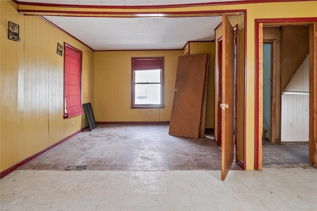 unfurnished room with tile patterned floors, wooden walls, and baseboards