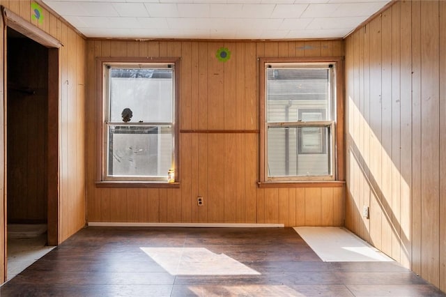 unfurnished room featuring wood finished floors, wood walls, and baseboards