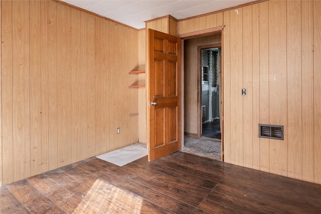 empty room featuring wood walls, visible vents, and hardwood / wood-style flooring
