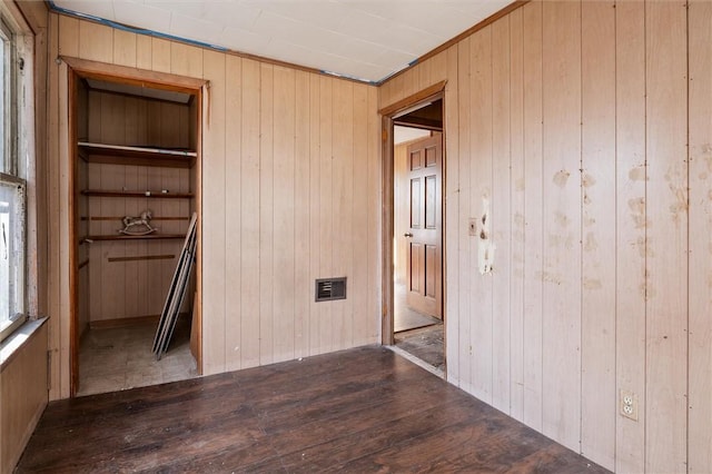 unfurnished bedroom with visible vents, wood walls, and wood finished floors