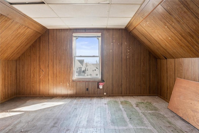 additional living space featuring wood walls, lofted ceiling, and hardwood / wood-style flooring