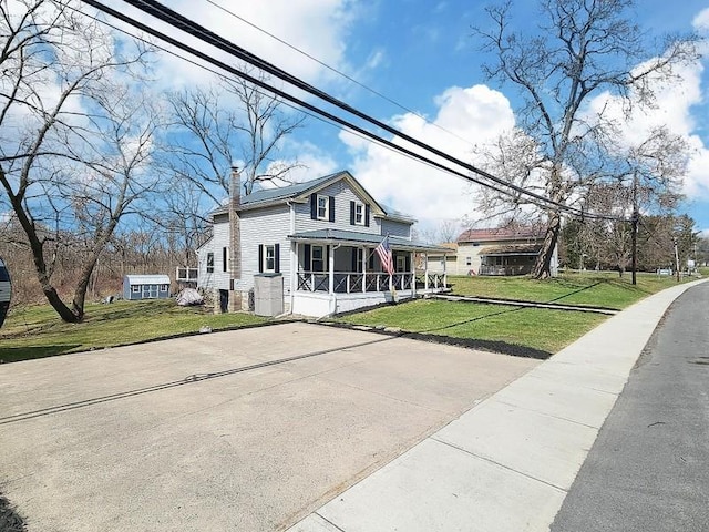 view of front of property featuring a chimney, covered porch, and a front lawn