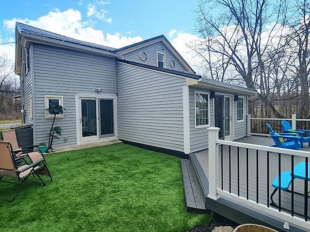 back of house featuring a deck and a lawn