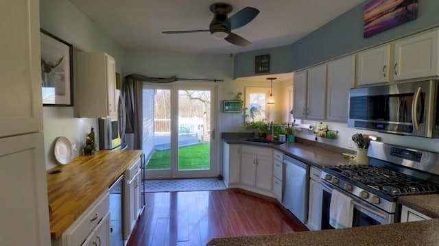 kitchen with a ceiling fan, white cabinets, appliances with stainless steel finishes, a sink, and wooden counters