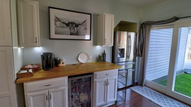 kitchen featuring butcher block counters, beverage cooler, white cabinetry, and stainless steel fridge