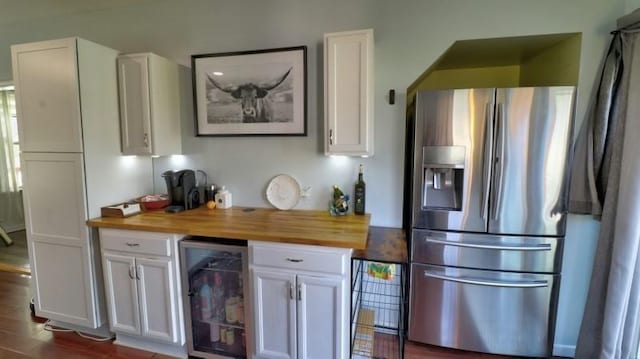 kitchen with stainless steel fridge with ice dispenser, butcher block countertops, white cabinets, and beverage cooler