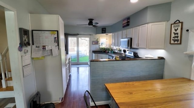 kitchen featuring appliances with stainless steel finishes, a ceiling fan, a peninsula, dark wood finished floors, and white cabinetry