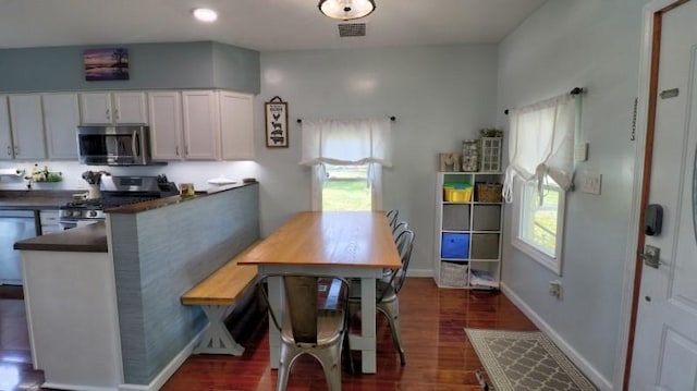 dining room featuring dark wood-type flooring, visible vents, and baseboards
