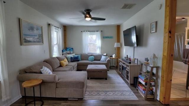 living room with visible vents, a ceiling fan, and dark wood finished floors