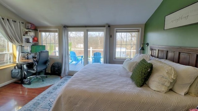 bedroom featuring baseboards, access to outside, wood finished floors, and lofted ceiling