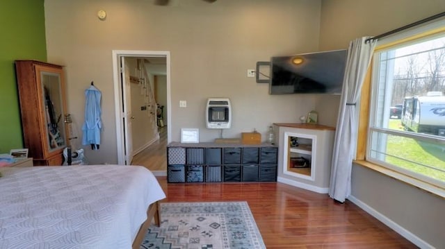bedroom with baseboards, heating unit, and wood finished floors