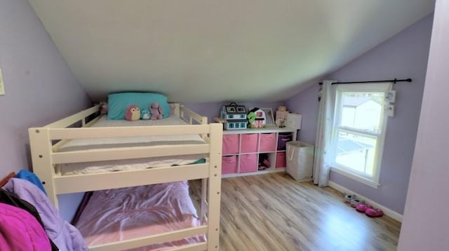 bedroom featuring light wood-style flooring, baseboards, and lofted ceiling
