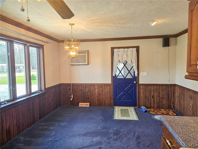 foyer entrance featuring a textured ceiling, wallpapered walls, visible vents, and a wainscoted wall