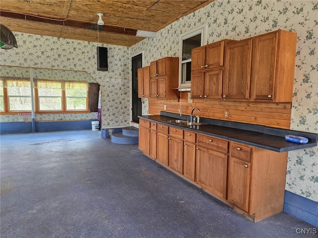 kitchen with wallpapered walls, a sink, and dark countertops