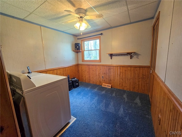 washroom featuring washer / clothes dryer, a ceiling fan, a wainscoted wall, wood walls, and visible vents