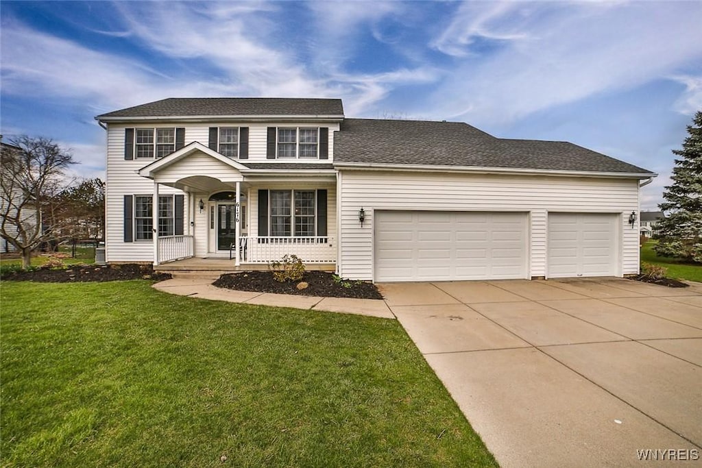 traditional-style home featuring a garage, a front yard, driveway, and covered porch