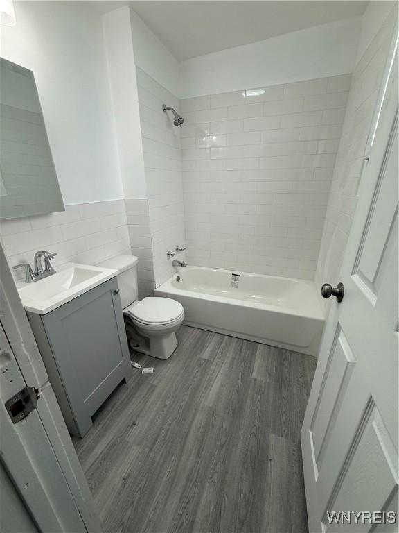72 Person St, Buffalo, NY 14212 - full bathroom featuring vanity, a wainscoted wall, toilet, wood finished floors, and tile walls